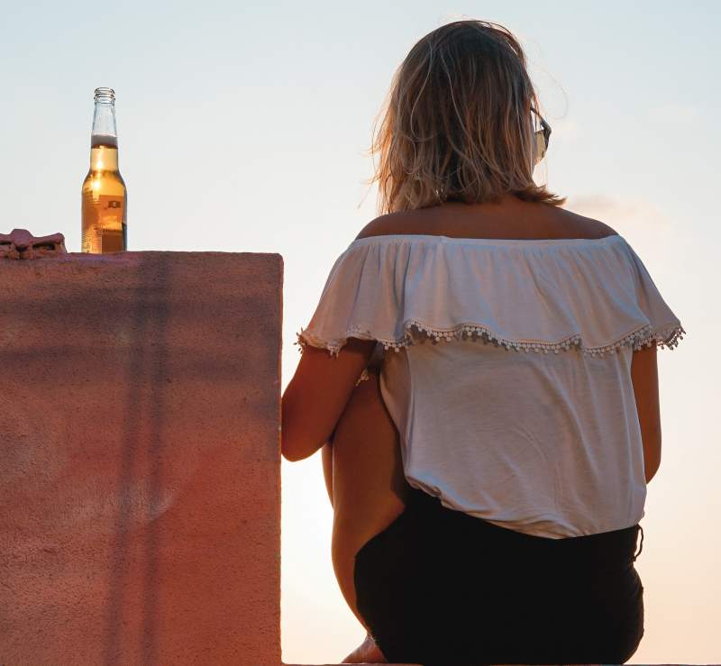 blonde woman next to bottle of beer