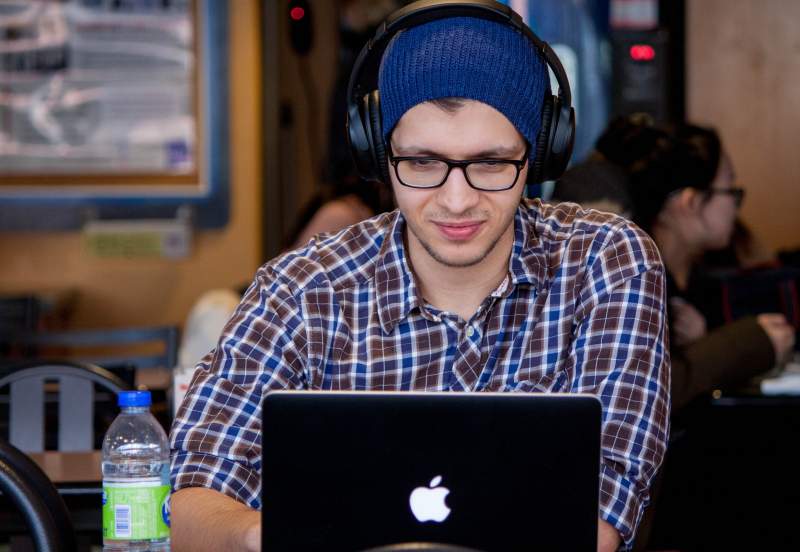 man with headphones on looking at laptop