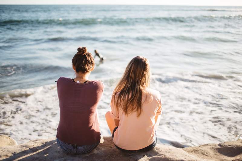 2 girls at the beach watching a surfer