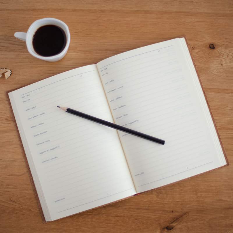 notebook on table below coffee mug