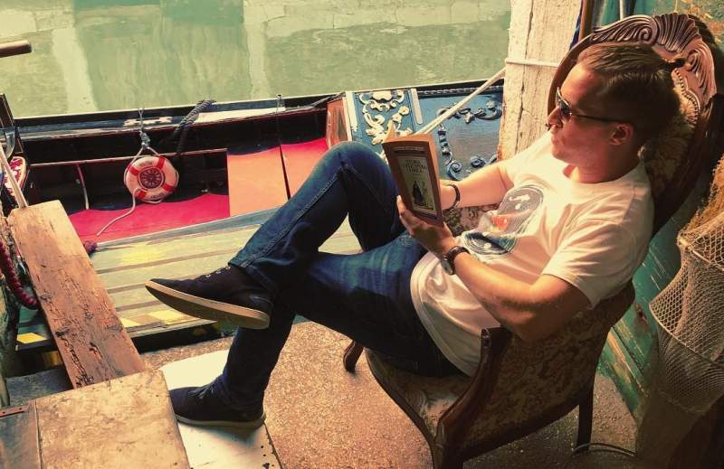 Olly Richards reading by the canal in Venice