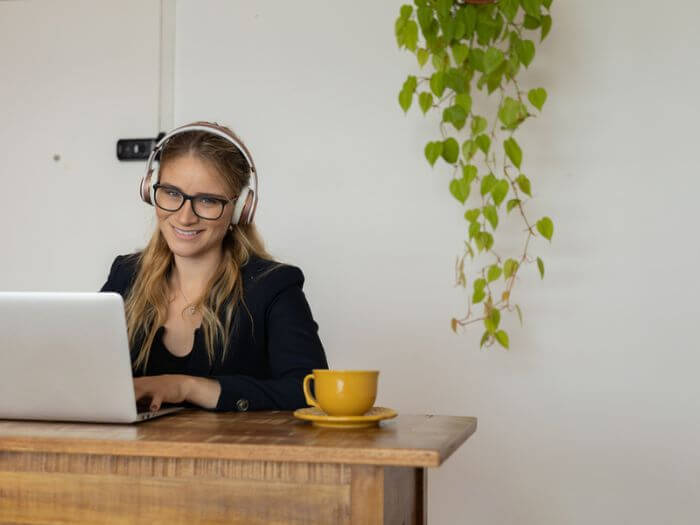 woman at desk with headphones working from home