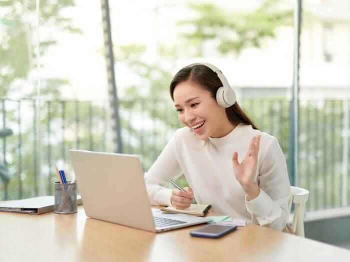 woman on laptop waving hello to online student