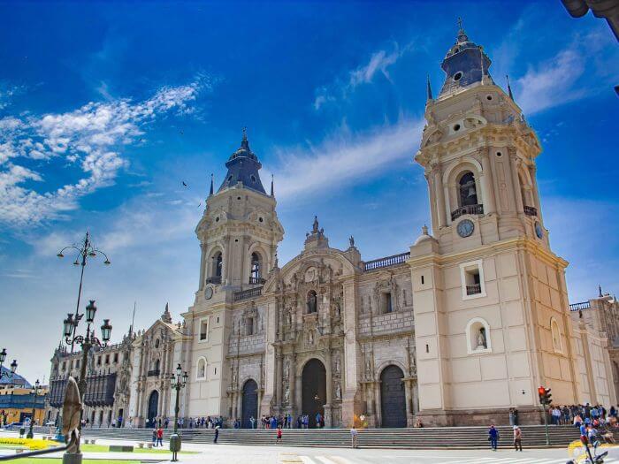 a large building with towers and people walking around with Cathedral of Lima in the background