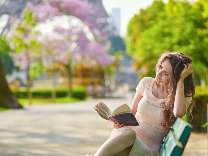 Woman reading book on bench with Eiffel Tower in the background