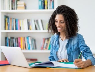 Woman studying at laptop, taking notes
