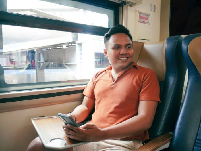 Smiling man on train with smartphone in hands