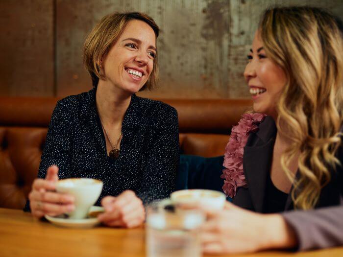 Two smiling women chatting over coffee